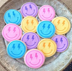 decorated cookies in the shape of smiley faces with lightning bolts on them are sitting in a bowl