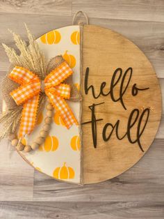 a wooden sign that says hello fall on it with a bow and pumpkins around it