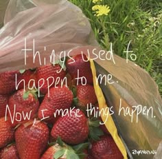 a bag full of strawberries sitting in the grass with a message written on it