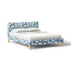 a bed with blue and white flowers on the headboard, made out of wood