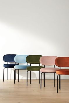 six chairs lined up against a white wall in an empty room with hard wood flooring