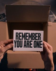 someone holding up a card that says, remember you are one in front of a cardboard box