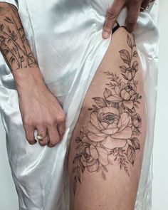 a woman's thigh with flowers on it and her hand resting on the leg