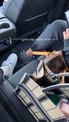 two children sitting in the back seat of a car, one holding a handbag