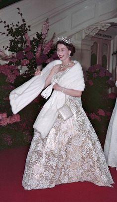 an old photo of a woman in a gown and fur stoler walking down the red carpet