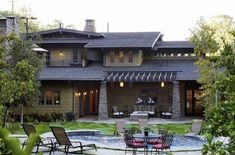 an outdoor patio with chairs and tables in front of a large house that is surrounded by trees