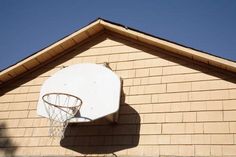 a basketball hoop mounted to the side of a house's wall with a blue sky in the background