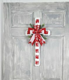 a cross decorated with red and white bows on the front door to give it a festive touch