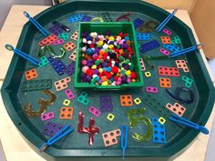 a green tray filled with lots of different colored beads and plastic pegs on top of it