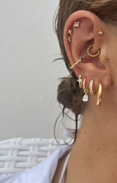 a woman wearing gold ear piercings with stars and moon designs