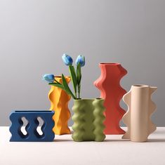 four different colored vases with flowers in them