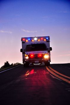 an ambulance with its lights on driving down the road