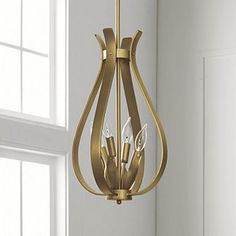 a gold chandelier hanging from the ceiling in a room with white walls and windows