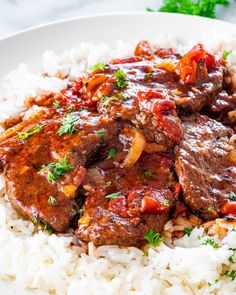 a white plate topped with rice and meat covered in gravy on top of it