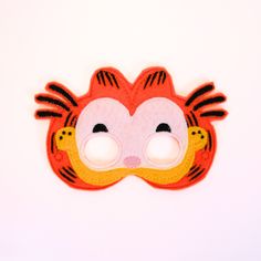 a red and yellow tiger mask with black stripes on it's face, sitting on a white surface