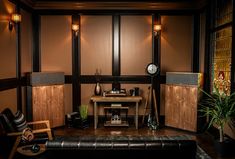 a living room filled with furniture next to a wall mounted speaker and a clock on top of a wooden table