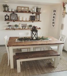 a dining room table with two benches and some shelves on the wall above it,