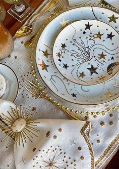 the table is set with gold and white plates, silverware, and napkins