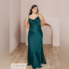 a woman in a long green dress posing for the camera with her hands on her hips