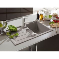 a kitchen sink sitting on top of a counter next to bowls and utensils