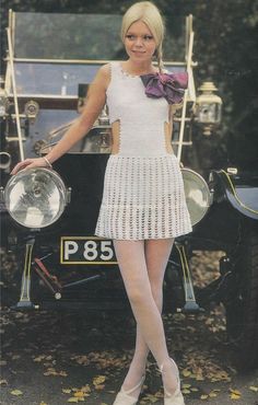 a woman posing in front of an old car