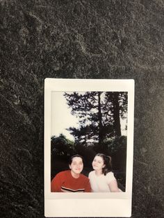 a polaroid photo of two people sitting next to each other on a black surface