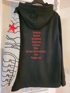 a black hoodie with red writing on the front and back, hanging in a closet