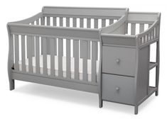 a gray crib with two drawers and a white sheet on the bottom half of it