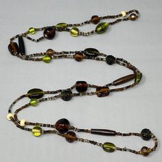 a long beaded necklace with multicolored glass beads and metal clasps on a white background