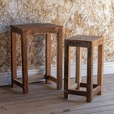 two wooden stools side by side against a wall