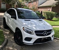 a white mercedes suv parked in front of a house