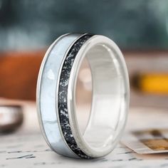 two wedding bands with black and white marble inlays are on top of each other