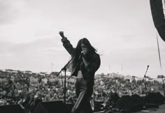 a woman standing on top of a stage holding a cell phone