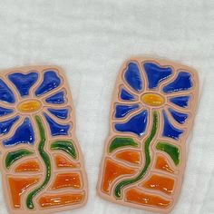 two colorful flower shaped tiles sitting on top of a white towel