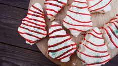 christmas cookies with red and white icing on a wooden board