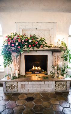 the fireplace is decorated with flowers and candles