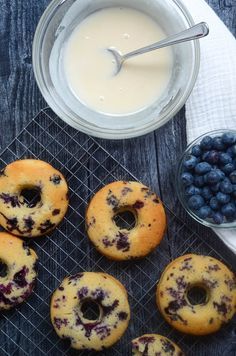 blueberry donuts cooling on a rack next to a bowl of yogurt