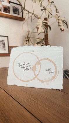 two wedding rings sitting on top of a wooden table next to a potted plant