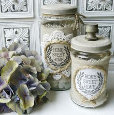 two jars with labels on them sitting next to some flowers