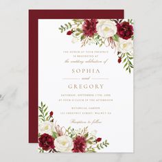 the burgundy and white floral wedding card is displayed on a marble surface with red accents