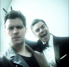 two men in tuxedos are posing for a photo with one man wearing antlers on his head