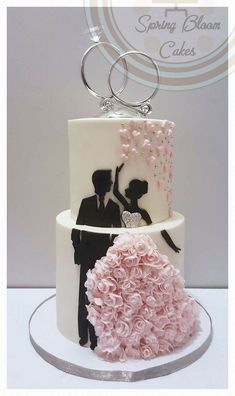 a wedding cake decorated with pink flowers and a bride and groom on the top tier