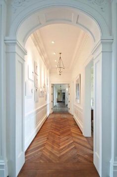 an archway leading to another room with wood floors and white walls, along with a chandelier hanging from the ceiling