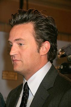 a close up of a person wearing a suit and tie