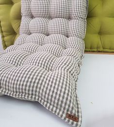 a close up of a pillow on a table with a chair in the back ground