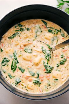 a pot filled with cheese and spinach on top of a white countertop next to a green leafy plant