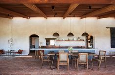 an outdoor kitchen and dining area with brick flooring, wood beams and exposed ceiling