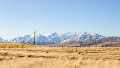 an open field with mountains in the background and snow on the top of the mountain