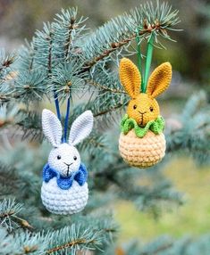 two crocheted easter bunnies hanging from a pine tree with blue and white ribbons