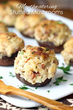 stuffed mushrooms on a white plate with a wooden spoon